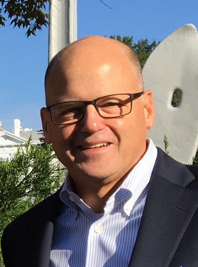 a man wearing a light blue collared shirt and suit coat, standing outside