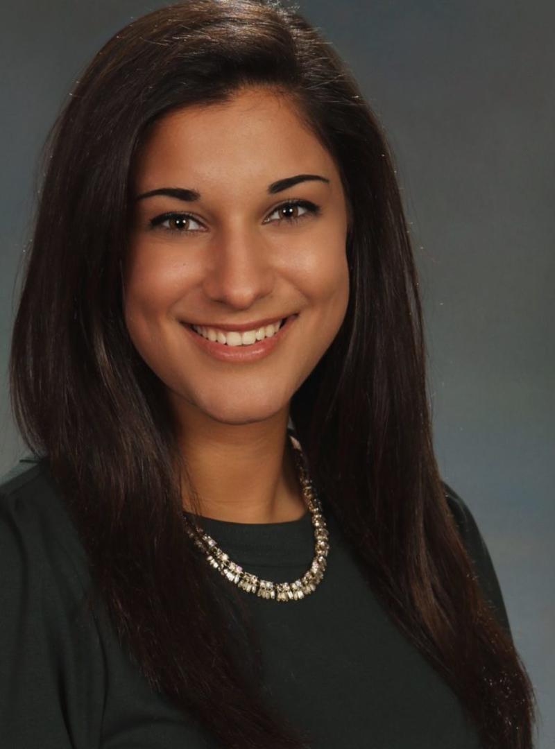 Rachel wears a black dress and a silver necklace in her headshot