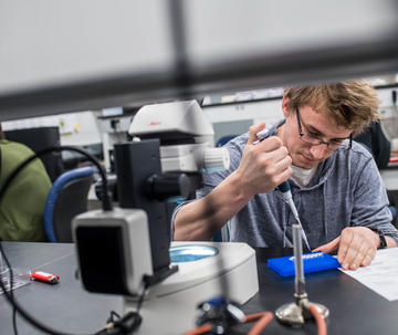 A student in the lab uses a pipette to measure samples