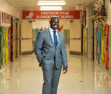 jabari whitehead, ed.d., wearing a suit and standing inside an elementary school hallway
