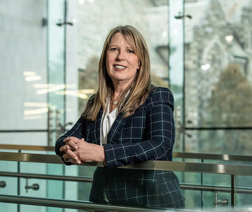 President Cheryl A. McConnell leaning against a glass panel