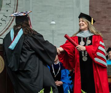 SJU President McConnell handing a diploma to a student at 2023 commencement