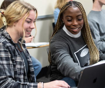 Two female Saint Joseph's students looking at laptop in classroom