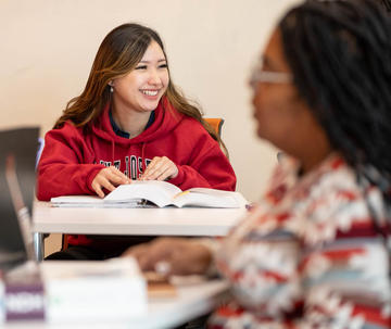 Female Saint Joseph's Lancaster student sitting at table with open textbook