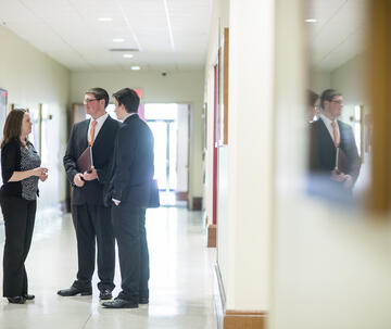 A group of students talk in the hallway in suits