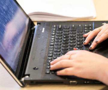 student typing on a laptop