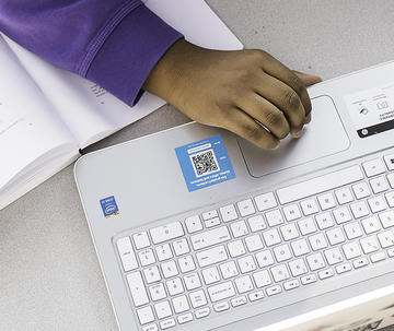 Hands are seen working on a white laptop