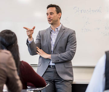 professor wearing a suit, teaching in front of class