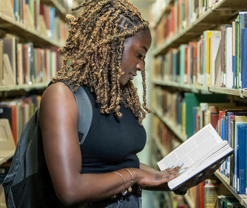 Saint Joseph's University student looking at a book in the library.