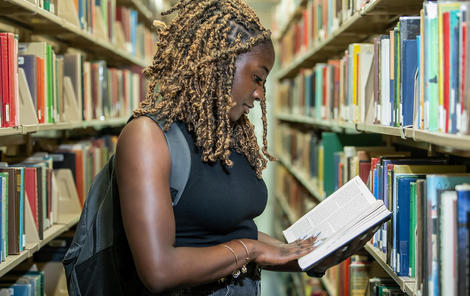 Saint Joseph's University student looking at a book in the library.