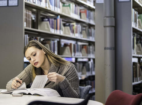 SEHD student studying in a library near shelf of books