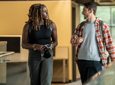 Two students having a conversation walking down the hall