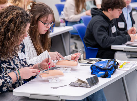 Two high school students practice suturing on a fake arm during their visit to Saint Joseph’s Lancaster location on Feb. 9.