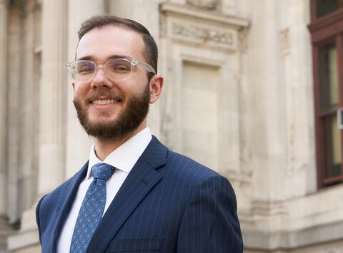 Man wearing navy suit standing in front of a building