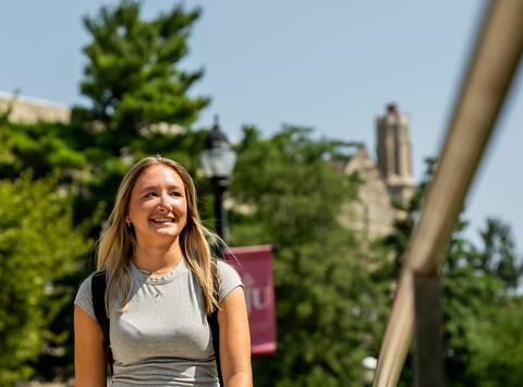 female student wearing gray shirt walking outside on Saint Joseph's campus