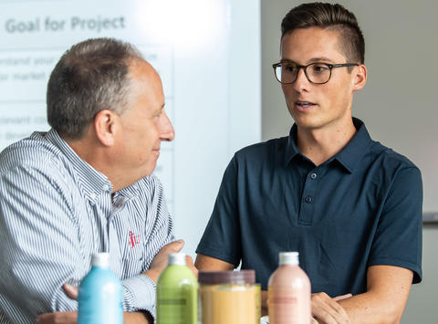 a food marketing student with glasses talking to a professor in the classroom
