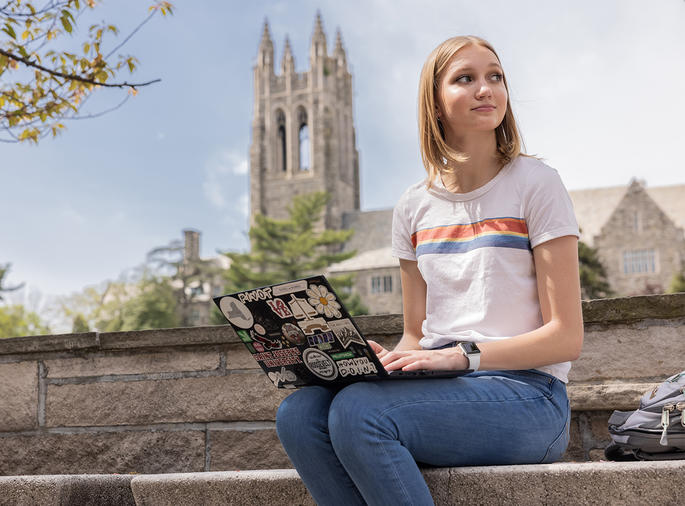 Female student seated with laptop outside