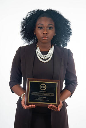 photograph of black woman in business dress holding a plaque