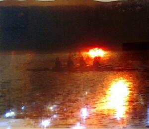 photograph of sunset on water with rowers
