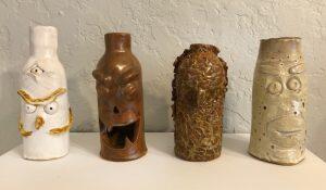 four ceramic jugs with faces on them