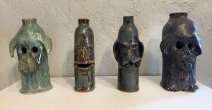 four ceramic jugs with faces on them