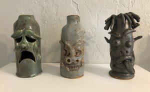 three ceramic jugs with faces on them