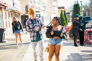 man holding a woman's braids on a public street