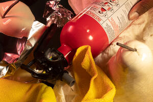 photograph of hand holding a fire extinguisher amidst apples