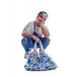 photo of a man in overalls holding a white bag with blue, paint-like splatters on it