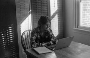 B+W photograph of light and shadows and man sitting in front of a computer