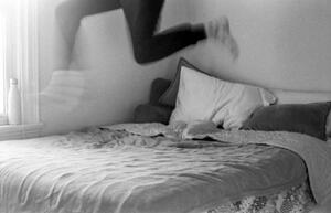 B+W photograph of blurred bottom legs of person jumping on bed