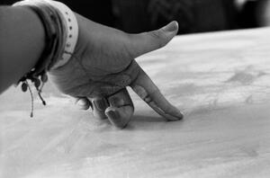 B+W photograph of finger pointing down to canvas
